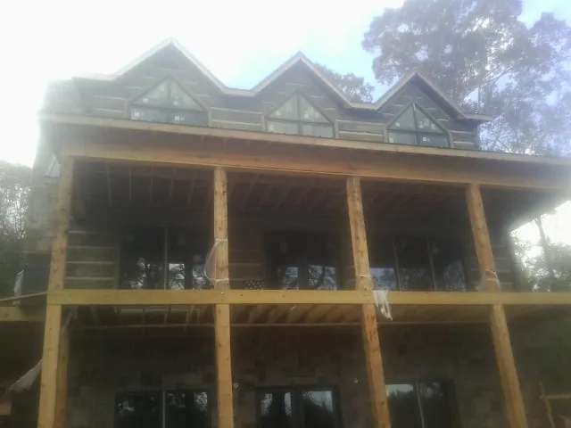 Dormers and porch framing on a large log home under construction — Roof Coating work by our crew in Weems