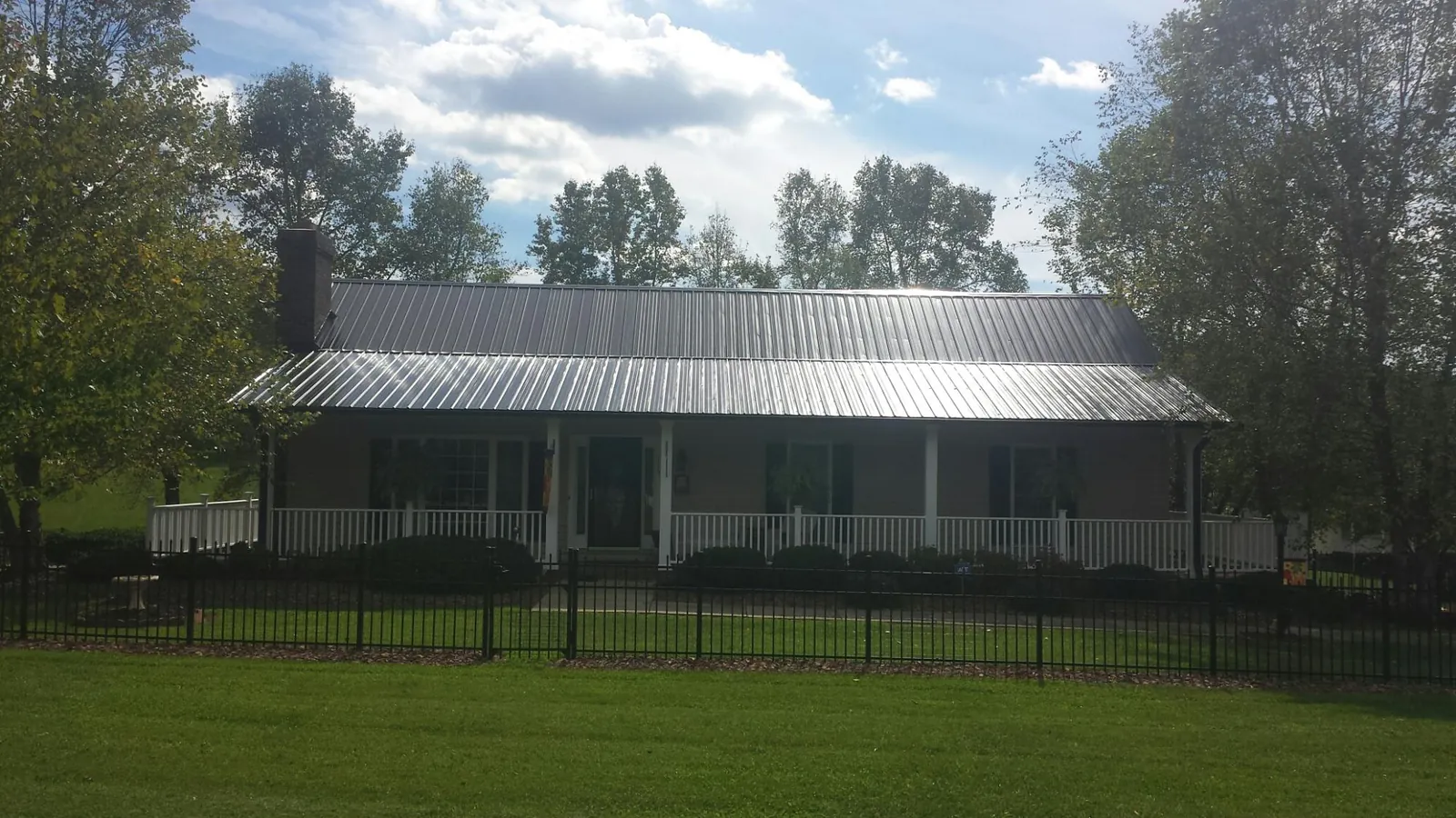 Gray metal roof on a brick ranch with a full width front porch — Gutter Guard Installation work by our crew in Weems